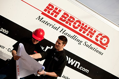 Two employees review an engineering drawing.